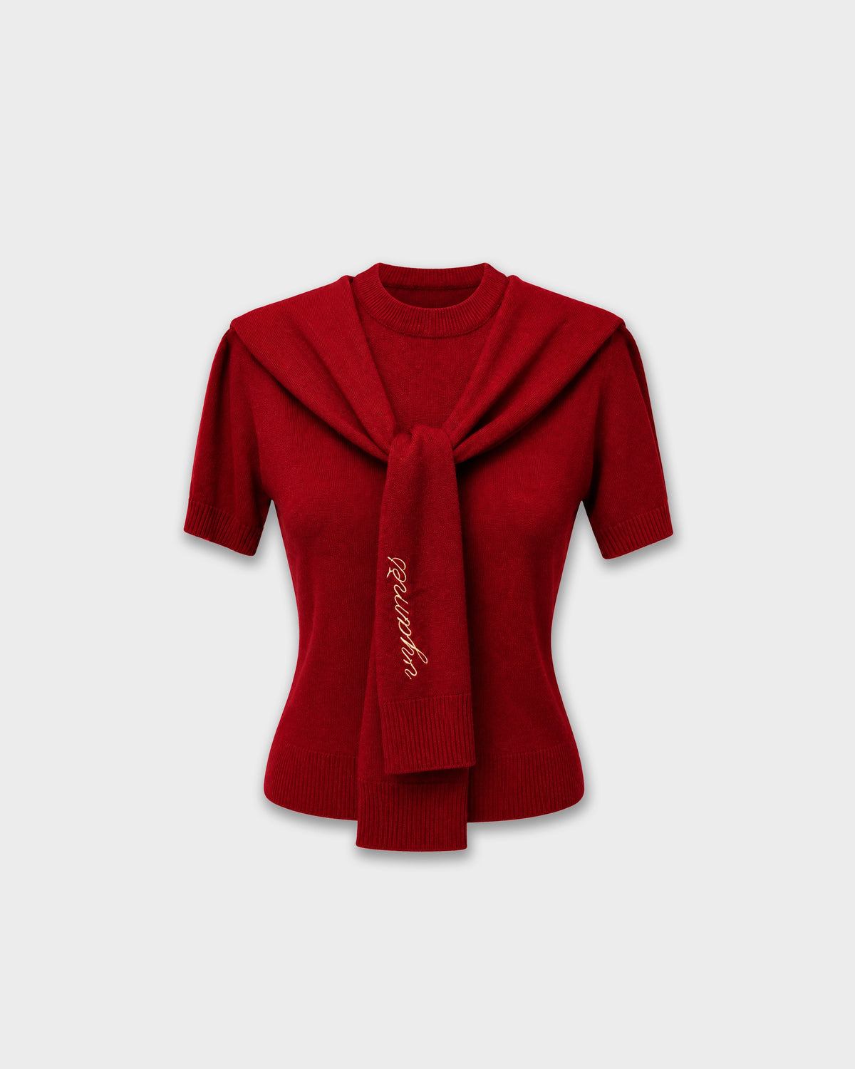 A red short-sleeve knit sweater with a wide collar and a front tie detail, featuring gold script embroidery on the tie, shown against a light gray background.