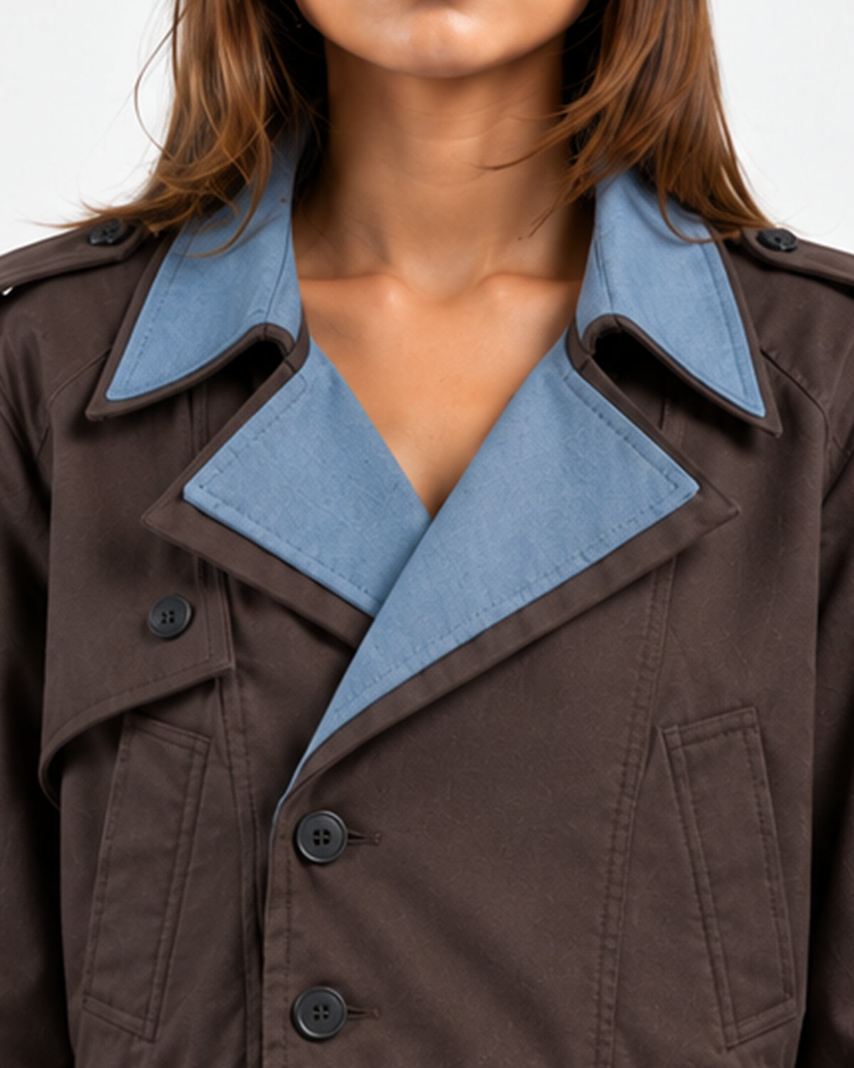 Close-up of a model wearing a brown trench coat with contrasting light blue inner collar lining.